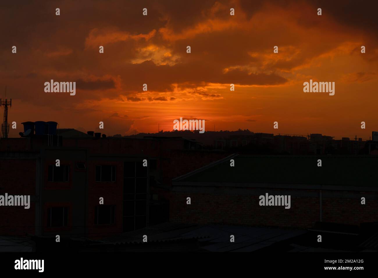 Crepuscolo arancione in città con antenna e silhouette di edifici Foto Stock