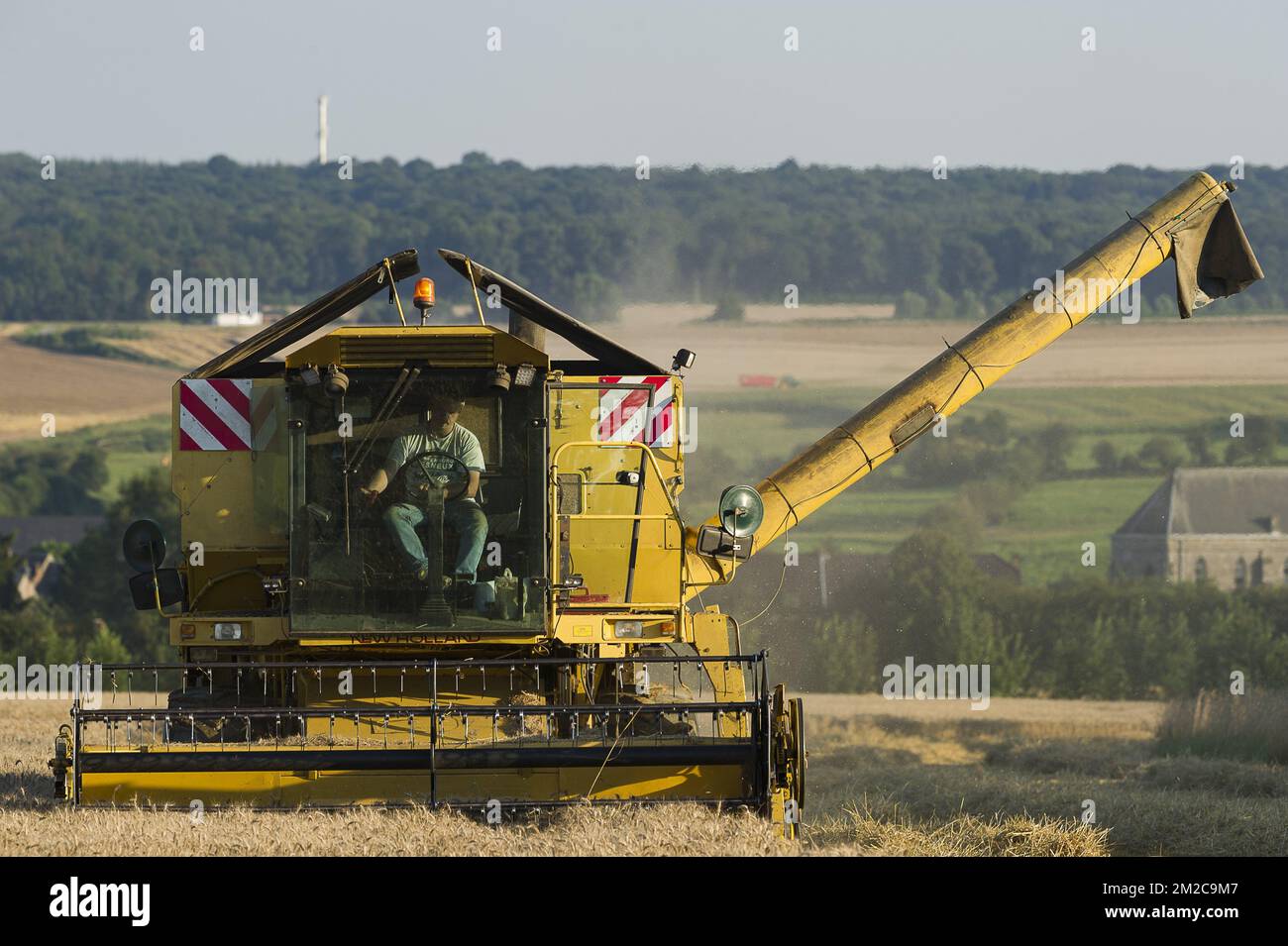 I coltivatori approfittano di alcuni giorni senza pioggia per raccogliere i loro campi. I semi vengono versati direttamente in un camion. La mietitrebbia assicura un processo di separazione delle sementi e del resto delle piante | Les agriculteurs profitent de quelques jours de beau temps, sans pluie, pour faire tourner les moissonneuses-batteuses dans leurs champs et récoulter les graines. Les graines sont directement separee de la paille. 15/08/2016 Foto Stock