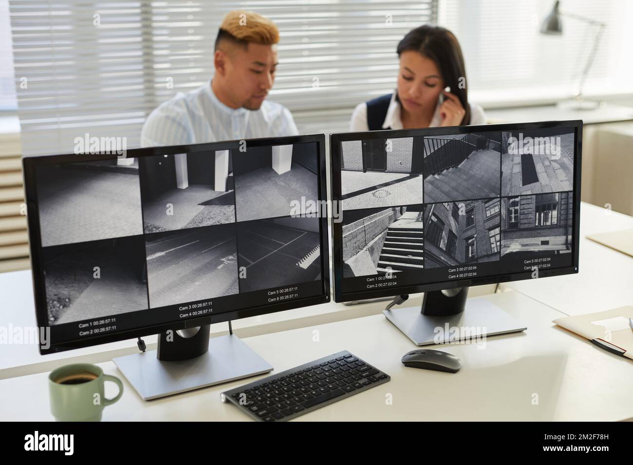 Immagine di sfondo di due schermi di computer con telecamere di sorveglianza multiple in ufficio di monitoraggio e sicurezza Foto Stock