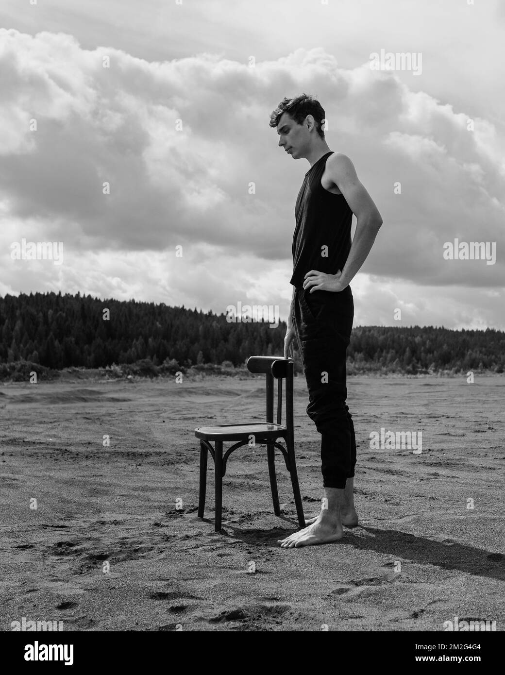 Lone Man stare vicino sedia nel deserto Foto Stock