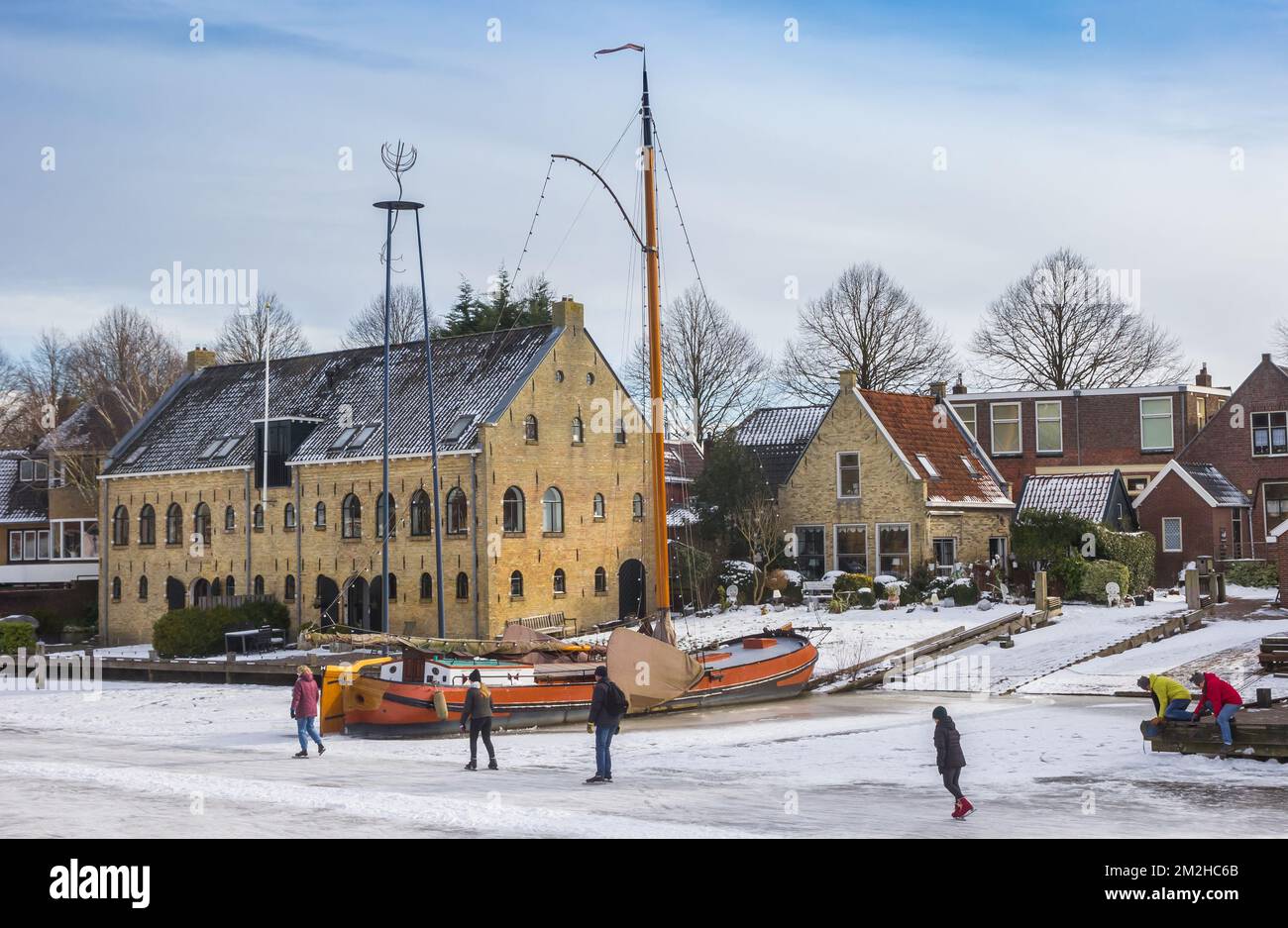 Persone che pattinano nelle acque ghiacciate del porto di Dokkum, Paesi Bassi Foto Stock