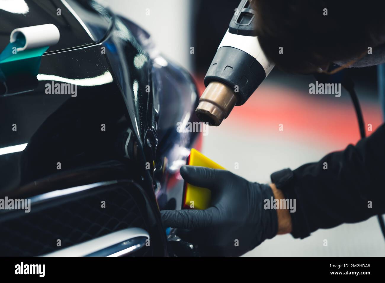 Processo di dettaglio auto - tintura di lampade per auto effettuata da un esperto in guanti protettivi con l'uso di attrezzature professionali. . Foto di alta qualità Foto Stock