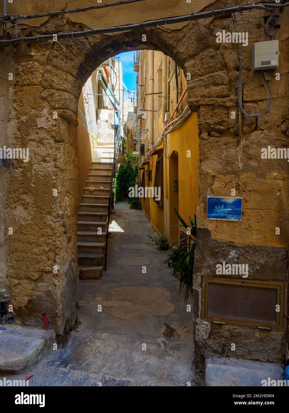 Un arco in pietra conduce ad uno stretto cortile nel centro storico di Trapani - Sicilia, Italia Foto Stock