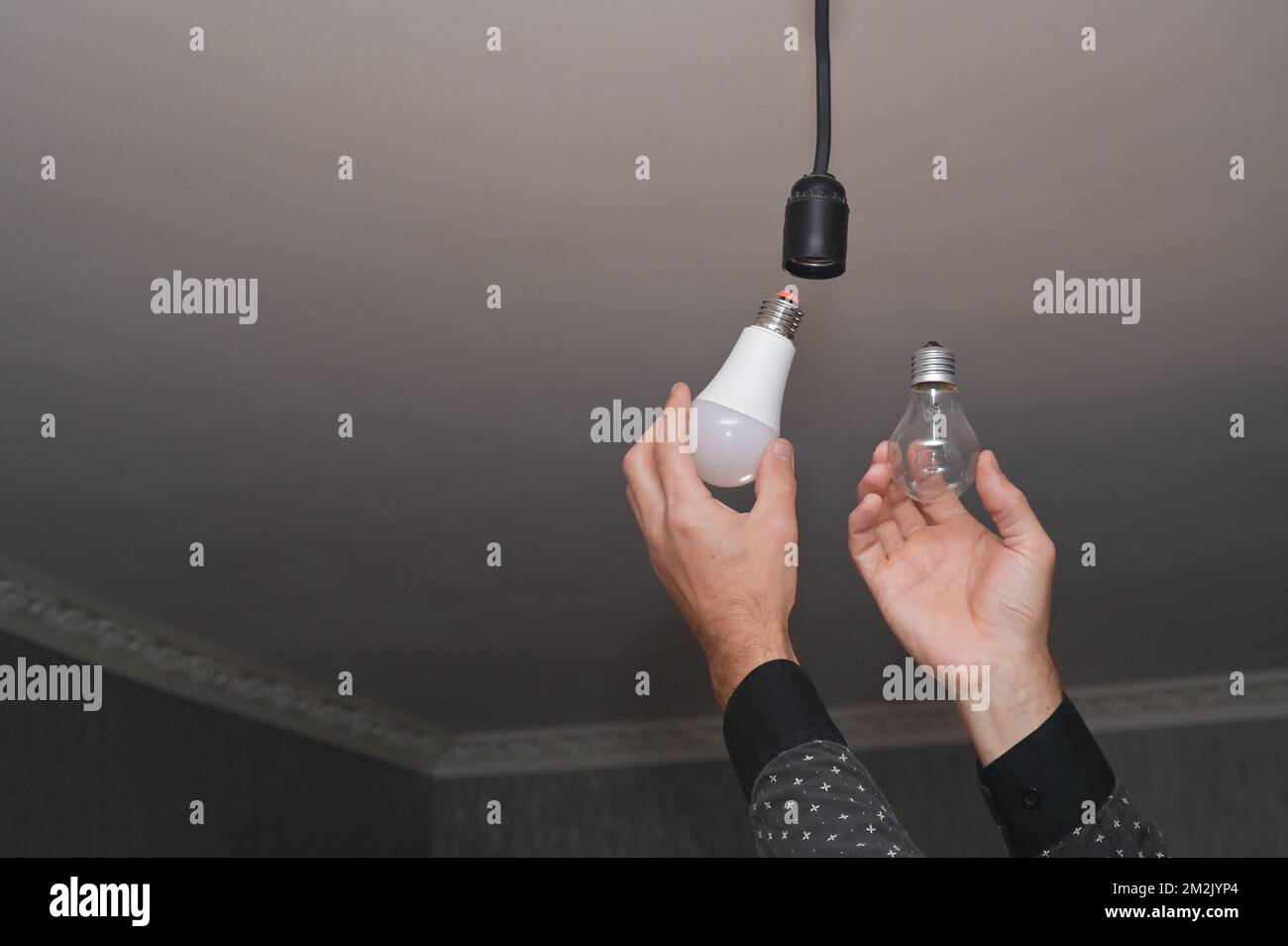 Il concetto di risparmio energetico. Lampada a incandescenza e lampada a LED a risparmio energetico nelle tue mani. Foto Stock