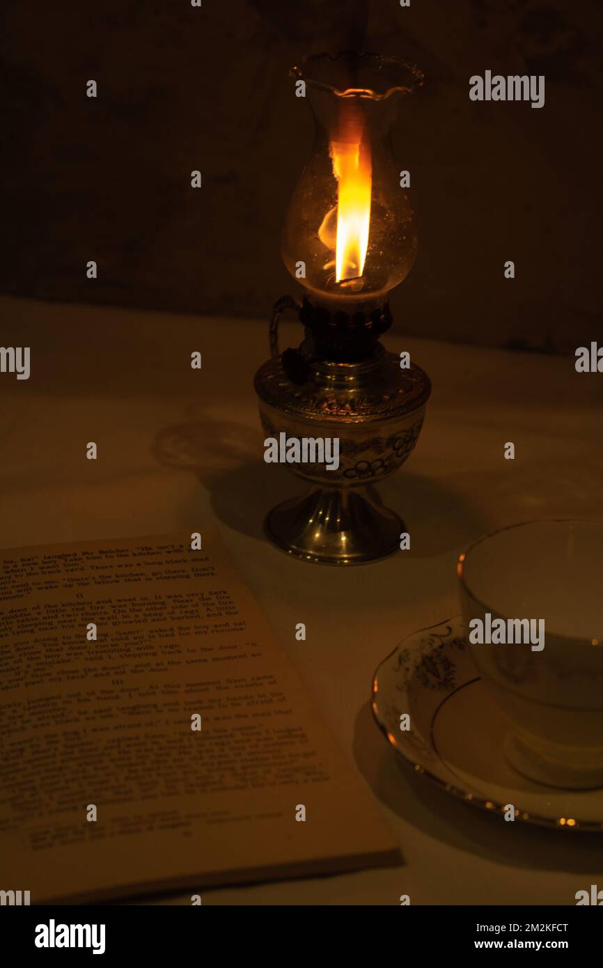 lampada kerazina fotolita vuota retrò tazza e vecchio libro aperto sul tavolo Foto Stock