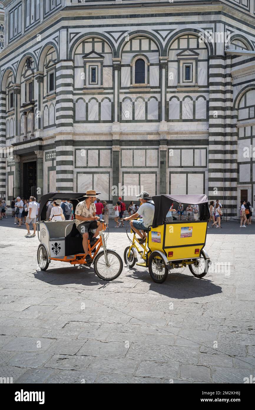 Firenze, Toscana / Italia - 15 giugno 2019: Due risciò seduti sul loro velotaxi di fronte al Battistero di San Giovanni a Firenze Foto Stock