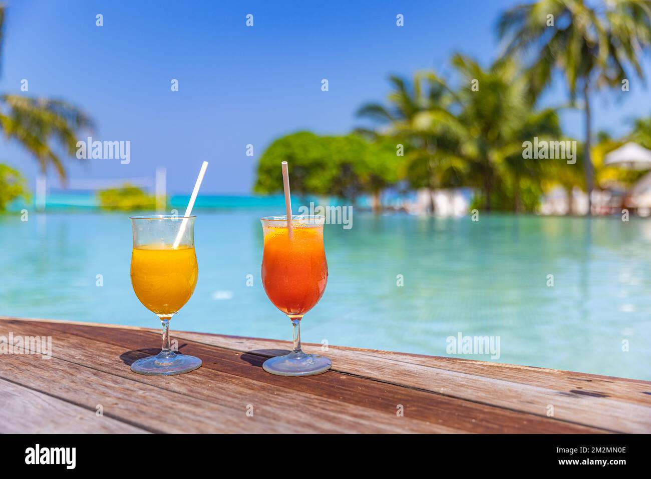 Cocktail colorati serviti nel lussuoso resort tropicale delle Maldive. Piscina con palme sfocate lettini ombrelloni. Piscina luminosa e soleggiata Foto Stock