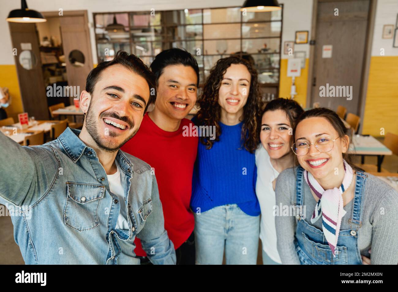 Gruppo multirazziale di giovani che prendono selfie indoor Foto Stock