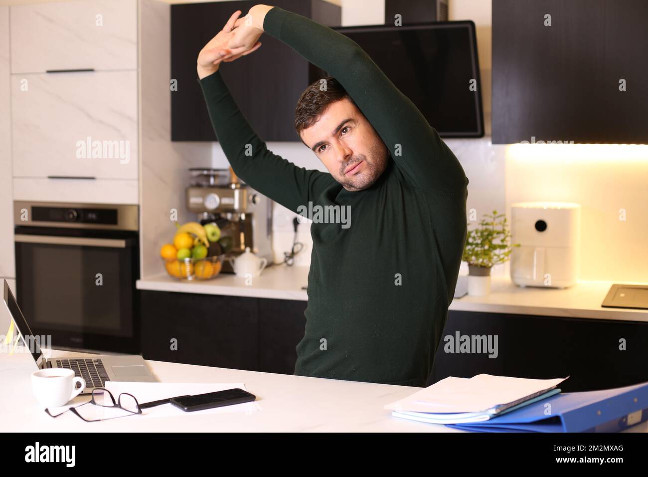 Uomo che si allunga in ufficio domestico Foto Stock