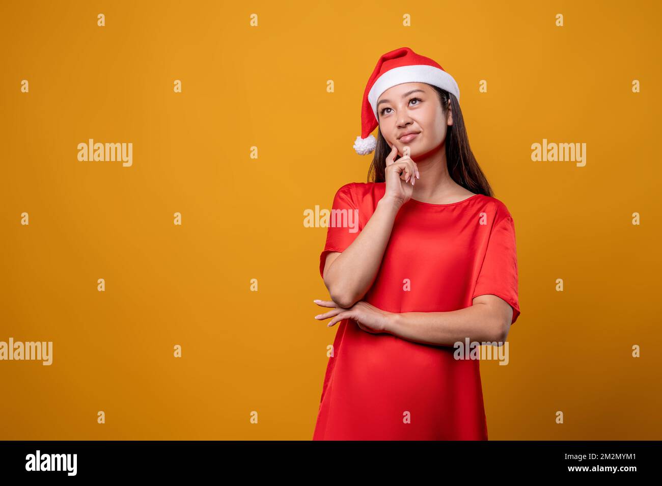 Giovane donna in vestito rosso e cappello di santa pensare a idee di sorprese Foto Stock