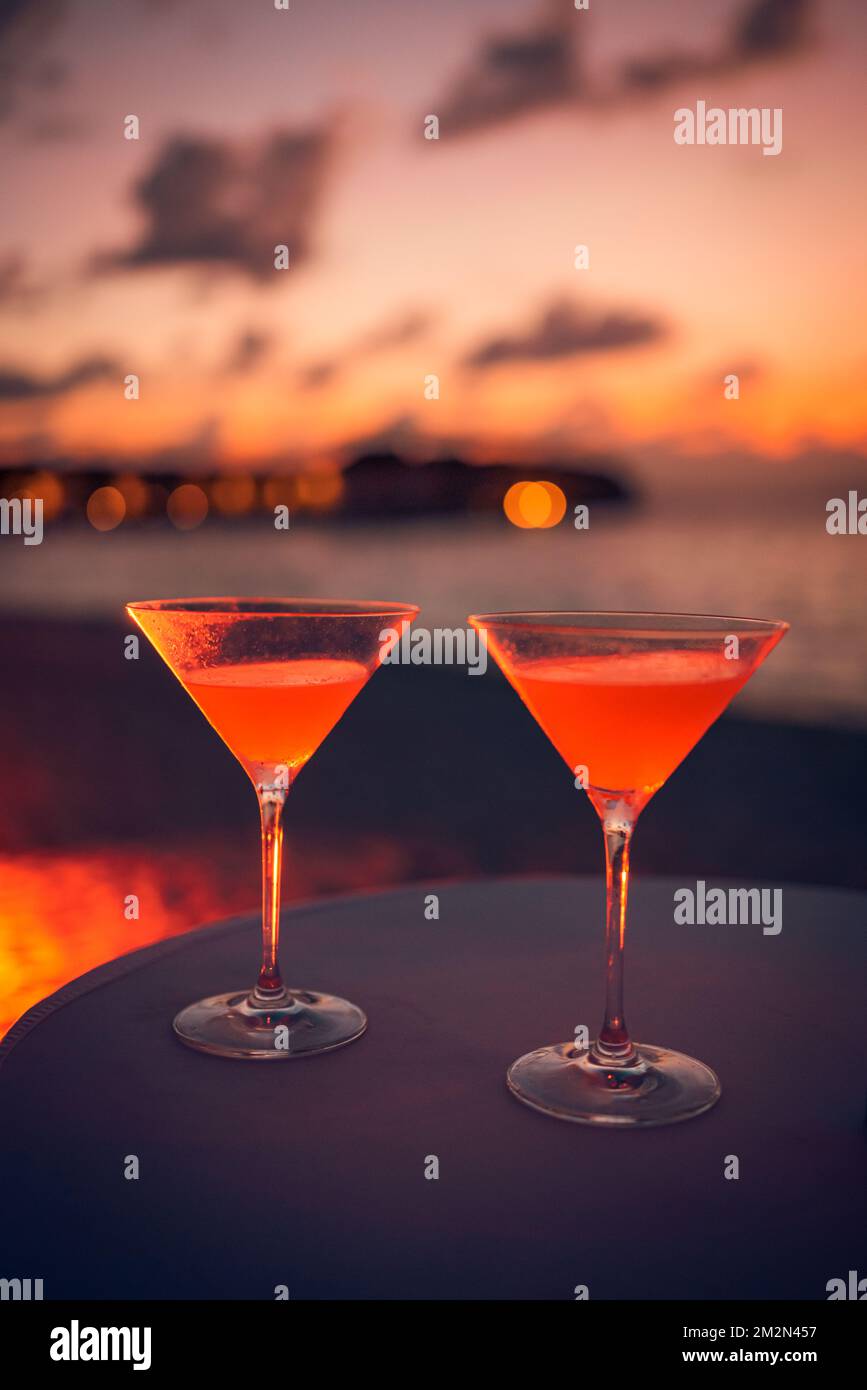 Due cocktail con spiaggia sfocata e cielo colorato al tramonto sullo sfondo. Stile di vita all'aperto di lusso, atmosfera rilassante e romantica Foto Stock