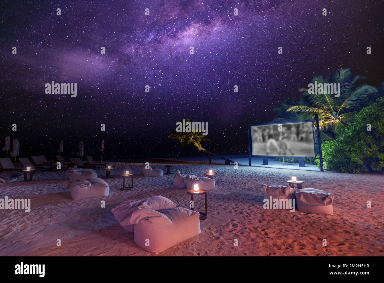 Serata di film sulla spiaggia di un'isola tropicale stellata. Vista panoramica incredibilmente tranquilla e rilassata del cinema all'aperto con la Via Lattea e le morbide candele delle palme Foto Stock