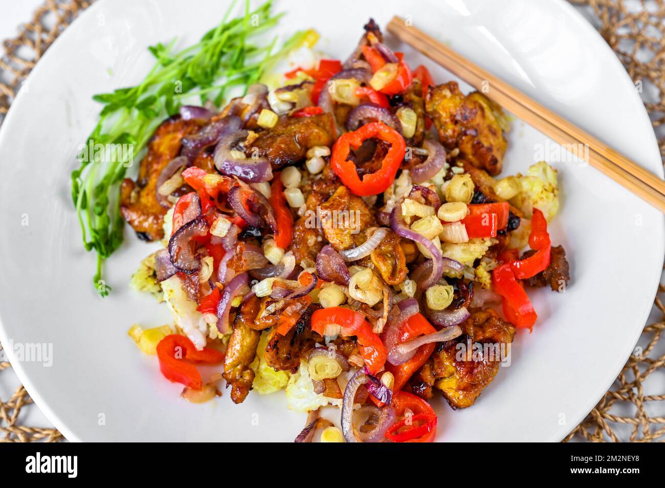 Pezzo di pollo arrosto con pepe rosso, peperoncino, cipolla, aglio con salsa di soia sul riso, bastone di carne sul piatto bianco. Cucina asiatica (vietnamita). Foto Stock