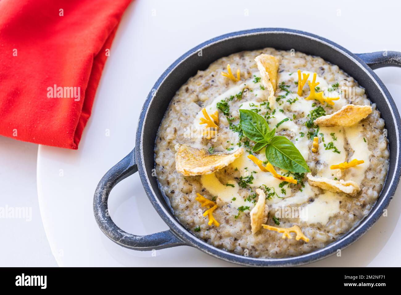 Cibo bello e gustoso su un piatto. Piatto gourmet su tavolo bianco con tovagliolo rosso, pasto speciale resort di lusso. Funghi al tartufo e verdure Foto Stock