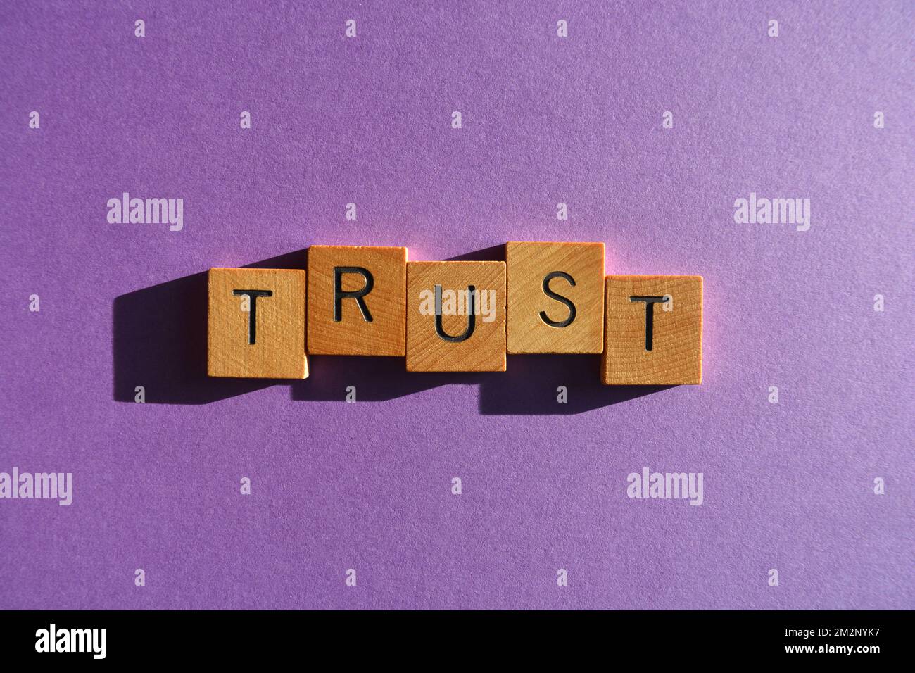 Fiducia, parola in lettere alfabetiche in legno isolato su sfondo viola Foto Stock