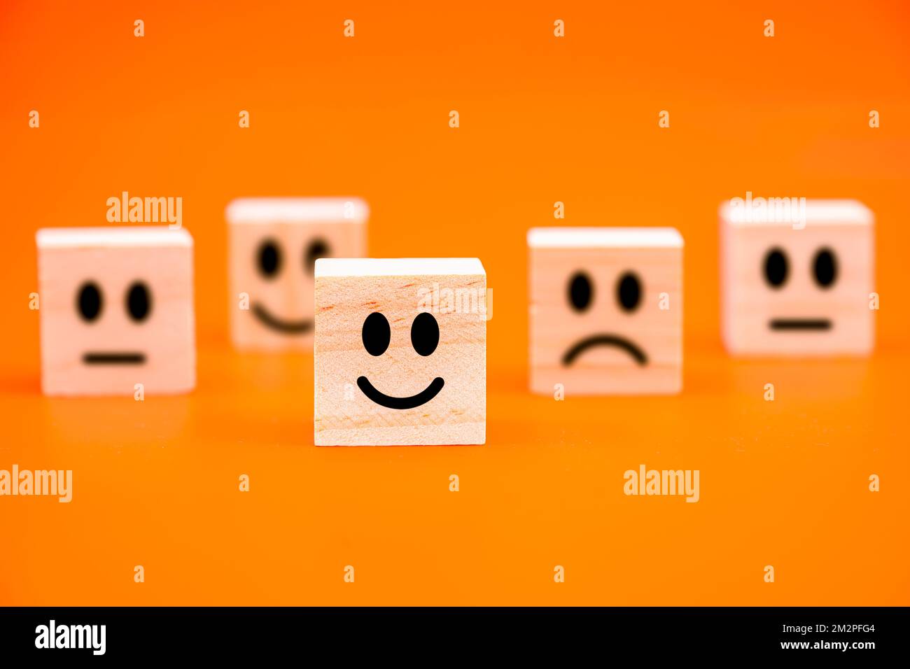 messa a fuoco selezionata happy face impresso su blocco di legno isolato su sfondo arancione Foto Stock