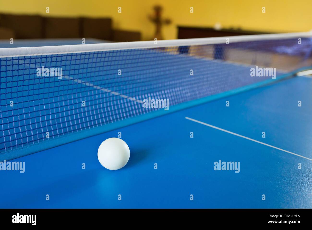 Una palla bianca da tennis per Ping-Pong su un tavolo blu. Un gioco Ping-Pong. Giochi sportivi Foto Stock