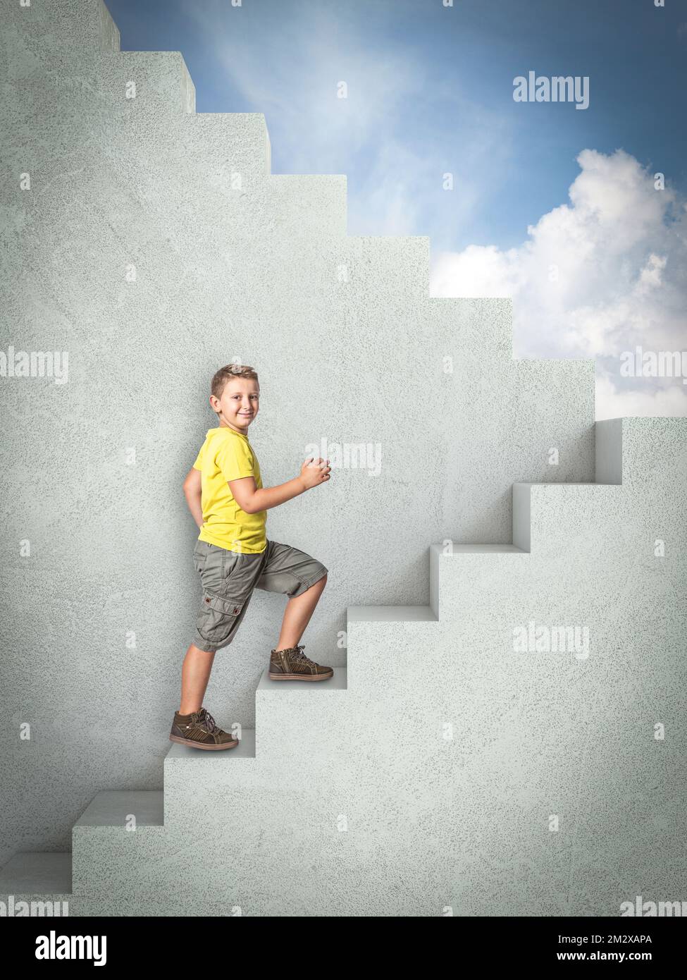 bambino sorridente che sale su scale di cemento. cielo blu sullo sfondo Foto Stock
