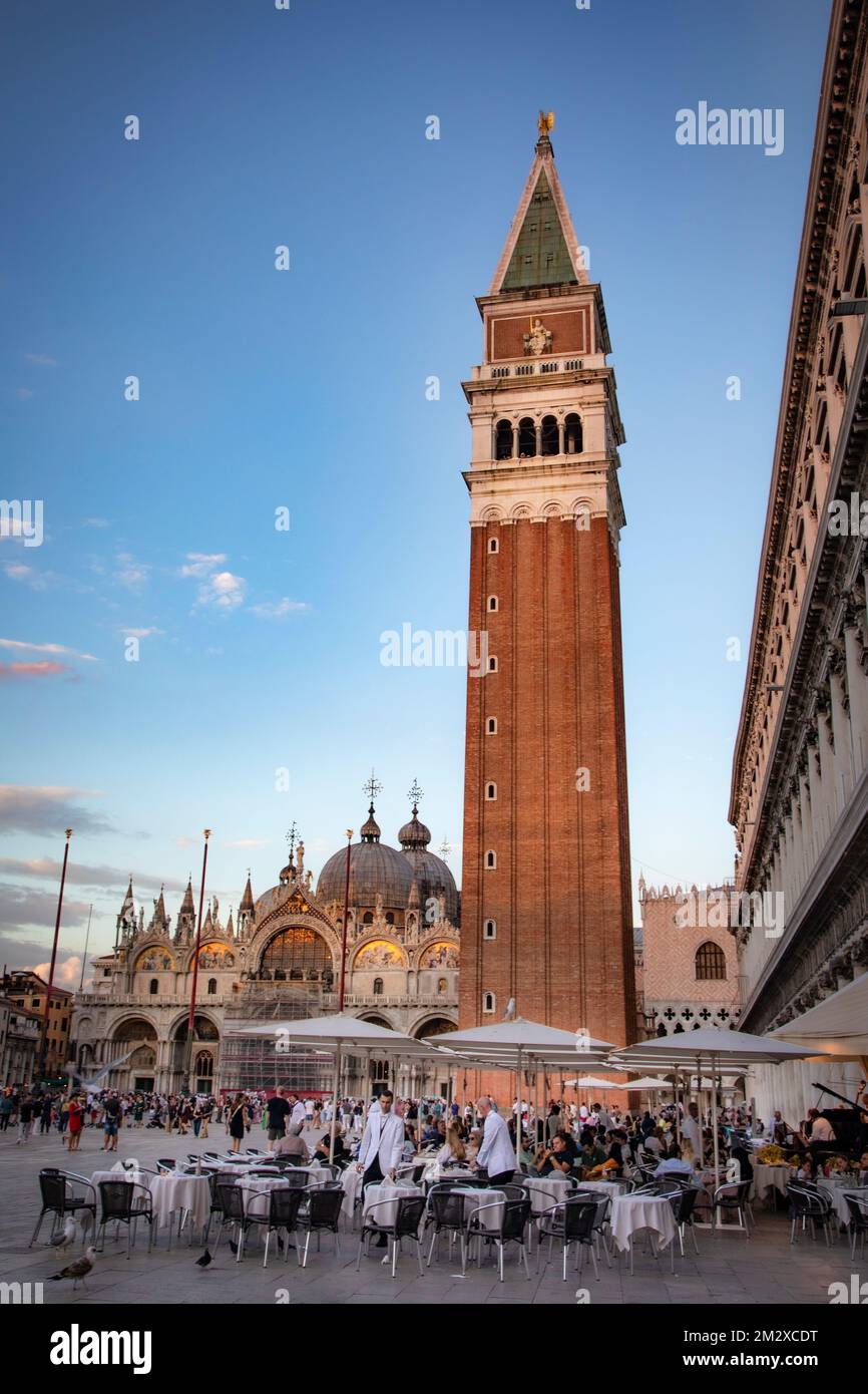 I Restrauteur preparano i loro tavoli al tramonto in Piazza San Marco, Venezia, Italia. Foto Stock