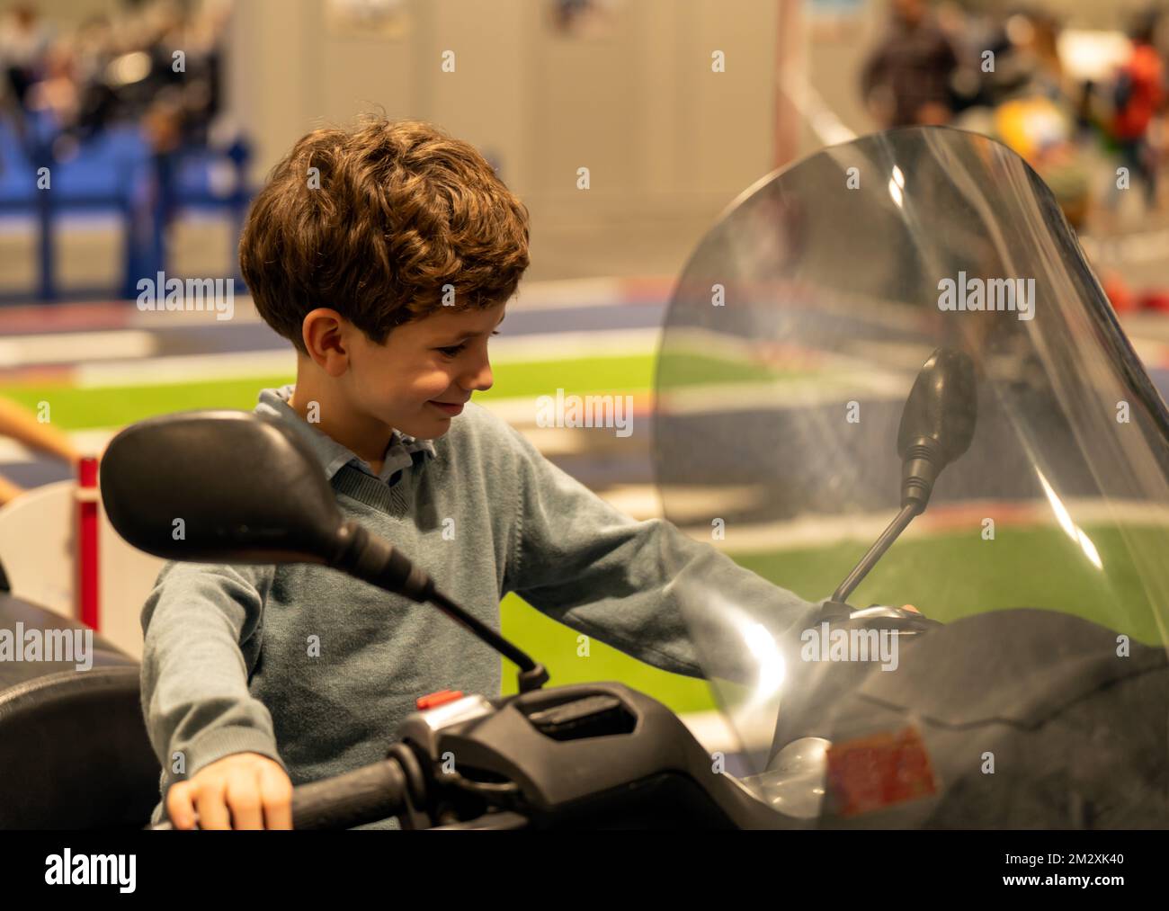 felice ragazzo godere il momento mentre si siede sopra una motocicletta della polizia che tiene i comandi Foto Stock