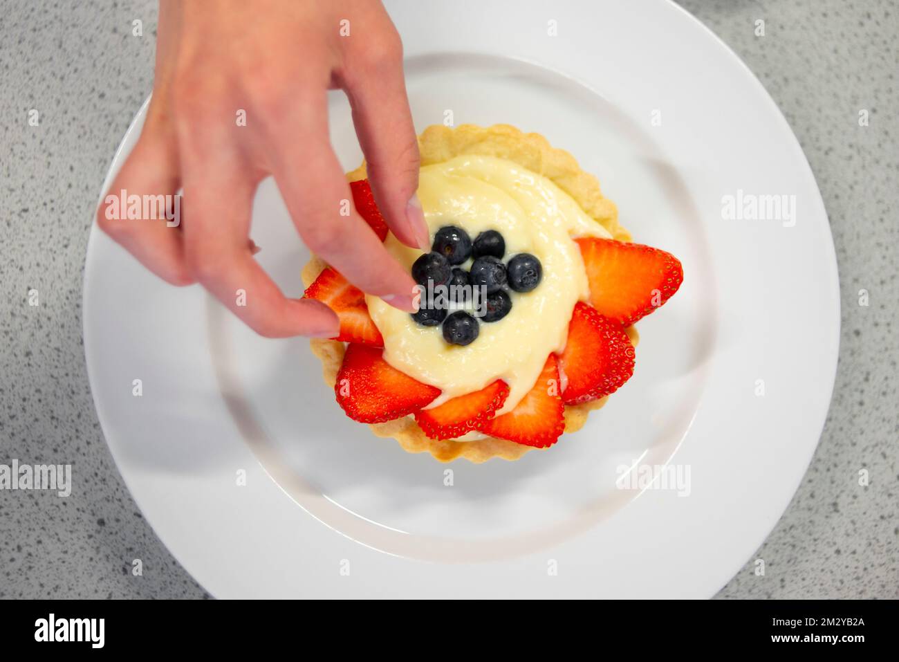 Primo piano di decorazione a mano crostata di fragole con mirtilli Foto Stock