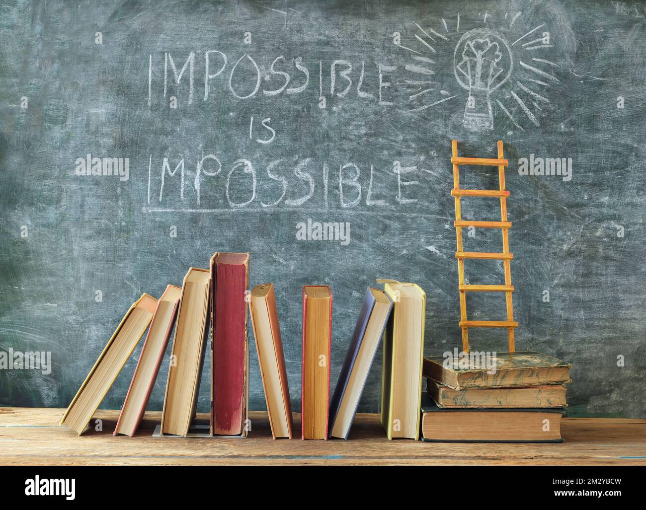 Stack di libri hardback con slogan impossibile è impossibile su blackboard.Learning, istruzione, sviluppo, scala di successo e di ritorno al concetto di scuola Foto Stock