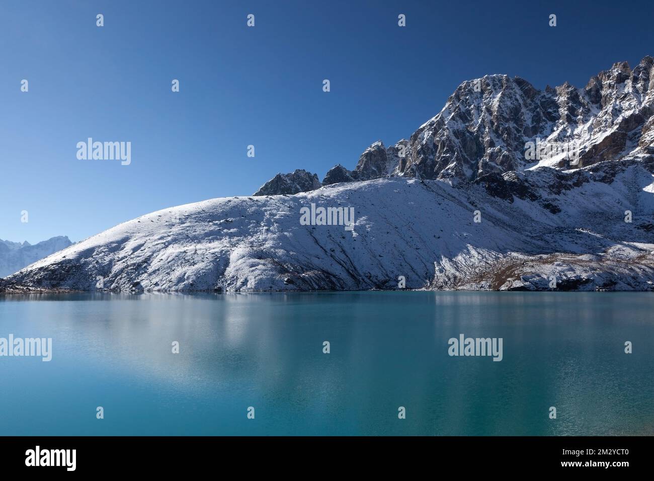 La splendida catena montuosa himalayana si riflette nelle increspature delle acque verdi smeraldo del lago Gokyo sotto il cielo azzurro e limpido in una giornata di sole. Foto Stock