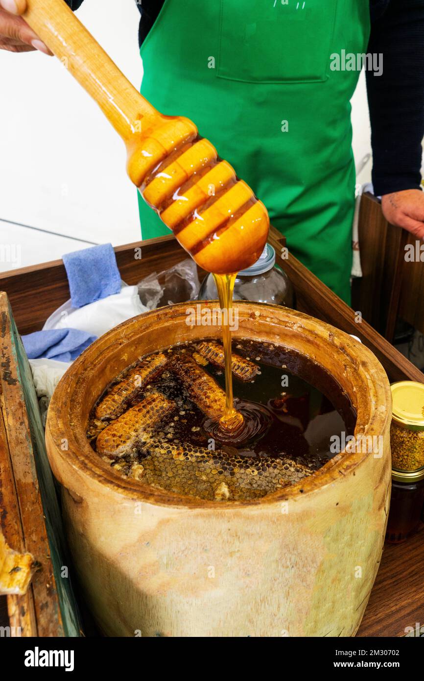 Cucchiaio di miele sepolto in un barile di fragrante miele fresco. Primo piano, concetto di alimentazione sana. Foto Stock