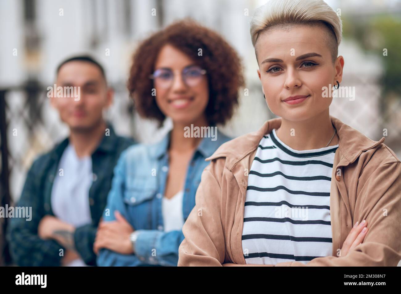Tranquilla donna caucasica in compagnia di persone biraciali Foto Stock