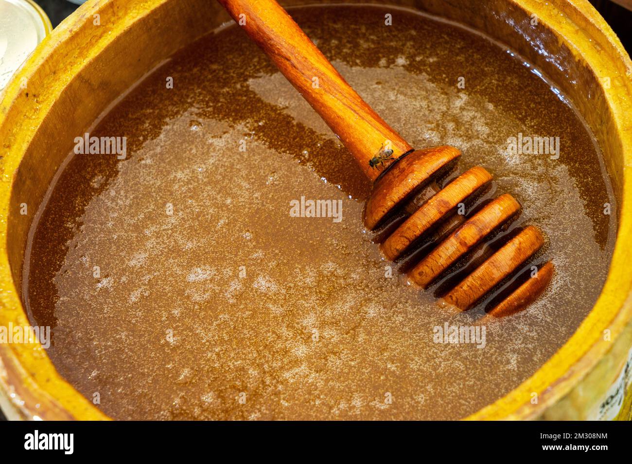 Cucchiaio di miele sepolto in un barile di fragrante miele fresco. Primo piano, concetto di alimentazione sana. Foto Stock