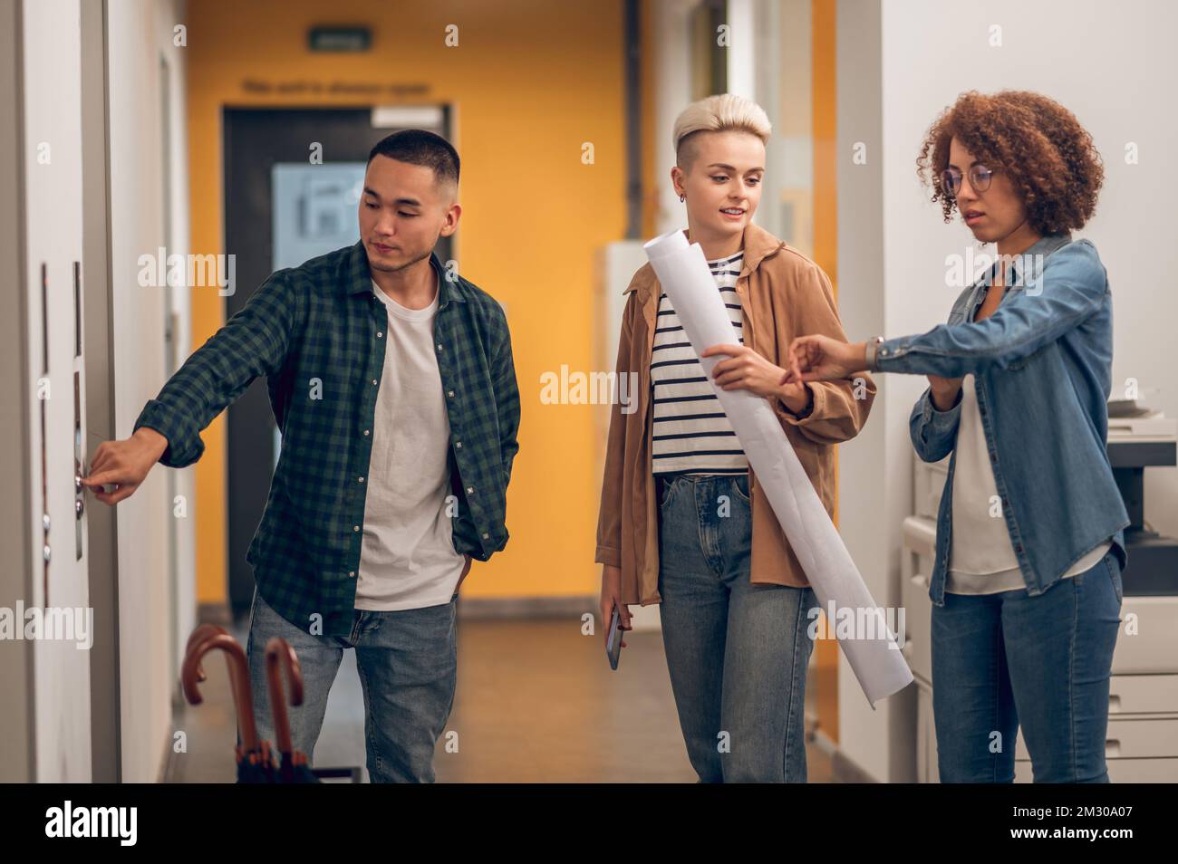 Three company employees standing at the elevator door Foto Stock