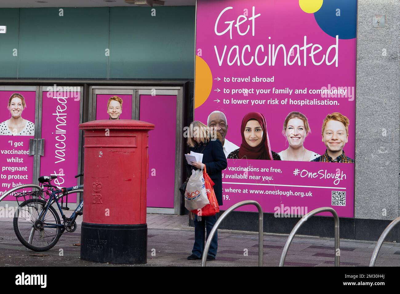 Slough, Berkshire, Regno Unito. 14th dicembre 2022. Una donna pubblica le cartoline di Natale in una casella postale in Slough High Street. I lavoratori della Royal Mail sono stati in sciopero oggi presso l'ufficio di smistamento di Slough in una disputa in corso sulle condizioni salariali e di lavoro. I membri della CWU hanno tenuto un picket ufficiale fuori dall'ufficio di smistamento, tuttavia, i manager e il personale dell'agenzia sono stati portati per continuare a consegnare la posta ai clienti. Credit: Maureen McLean/Alamy Live News Foto Stock