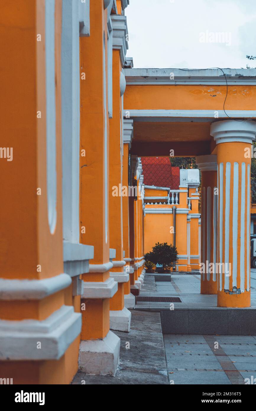 Una foto verticale di un edificio con colonne bianche e arancioni. Foto Stock