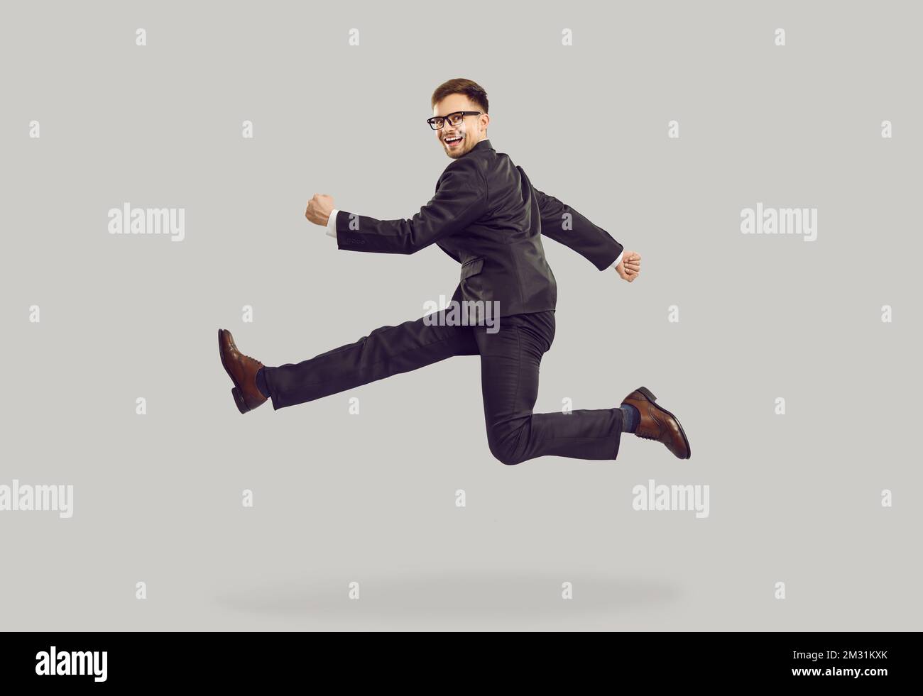 Giovane uomo caucasico che salta e sorride in posa di runner vestito in stile business Foto Stock