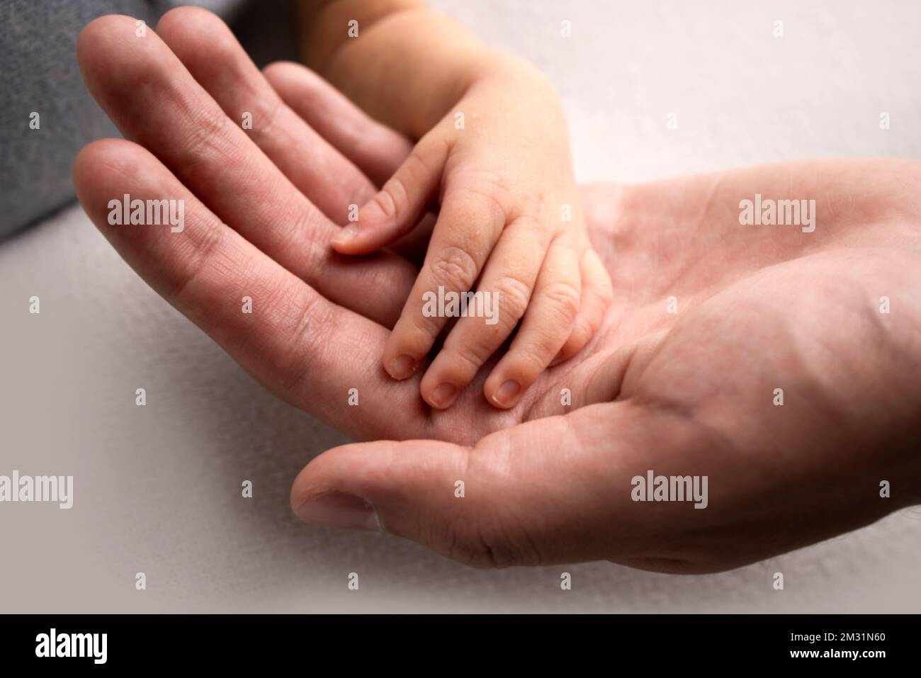 La piccola mano del figlio con piccole dita giace sul palmo del padre. Foto Stock