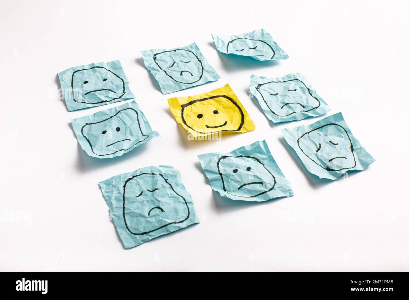 Un volto triste che guarda i volti sorridenti da lontano. Volti felici e tristi disegnati su adesivi blu. Concetti di esclusione, differenza, gelosia. Alta qualità pho Foto Stock