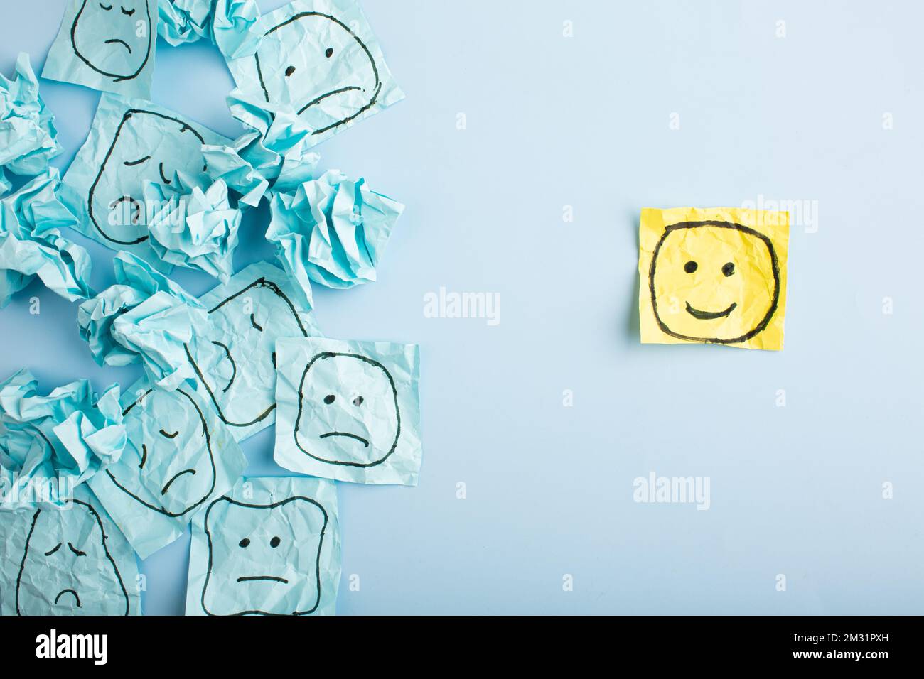 Un volto triste che guarda i volti sorridenti da lontano. Volti felici e tristi disegnati su adesivi blu. Concetti di esclusione, differenza, gelosia. Alta qualità pho Foto Stock