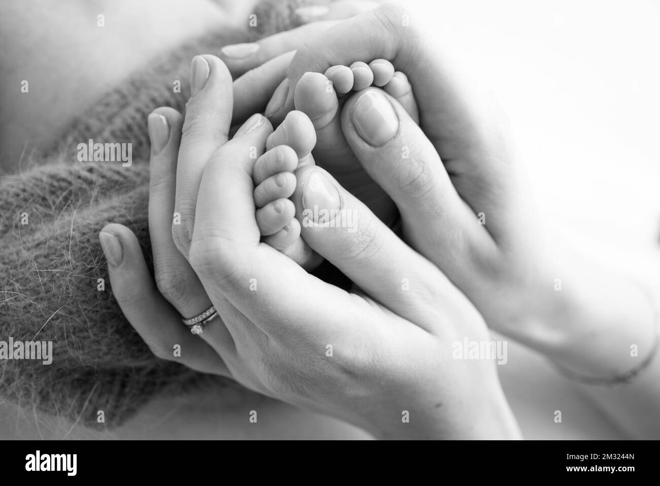 Gambe, dita dei piedi, piedi e talloni di un neonato. Le mani della madre tengono le gambe del bambino. Foto Stock