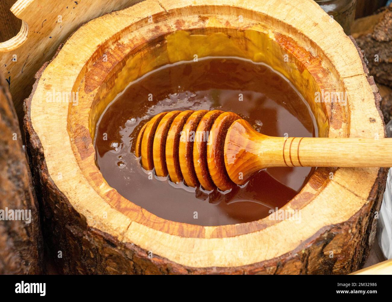 Cucchiaio di miele sepolto in un barile di fragrante miele fresco. Primo piano, concetto di alimentazione sana. Foto Stock