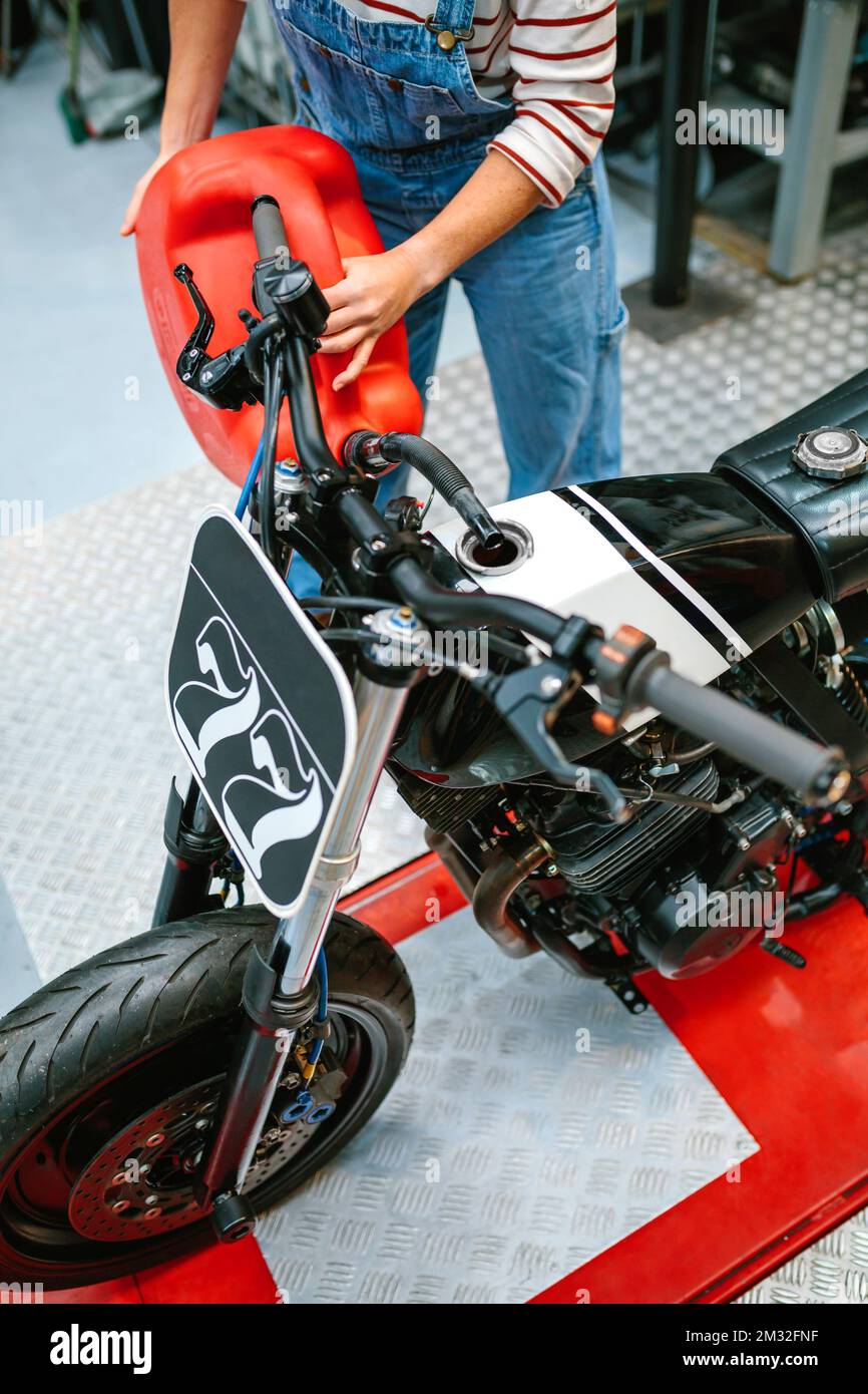 Donna meccanica con jerry può riempire serbatoio carburante di moto in fabbrica Foto Stock