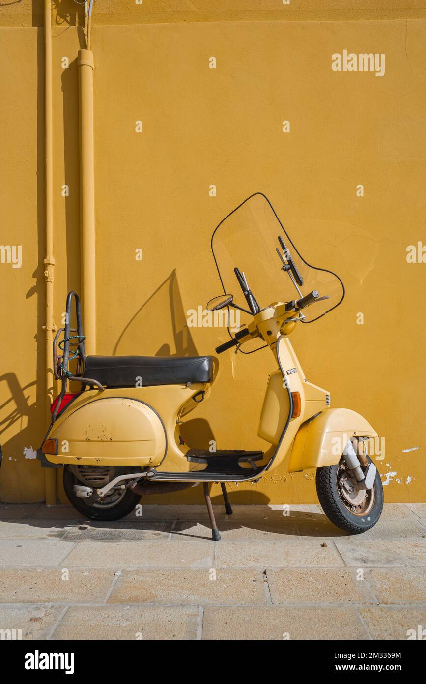 Scooter Italia, vista in estate di uno scooter Vespa parcheggiato contro una parete gialla nella città veneziana di Chioggia, Veneto, Italia, Foto Stock