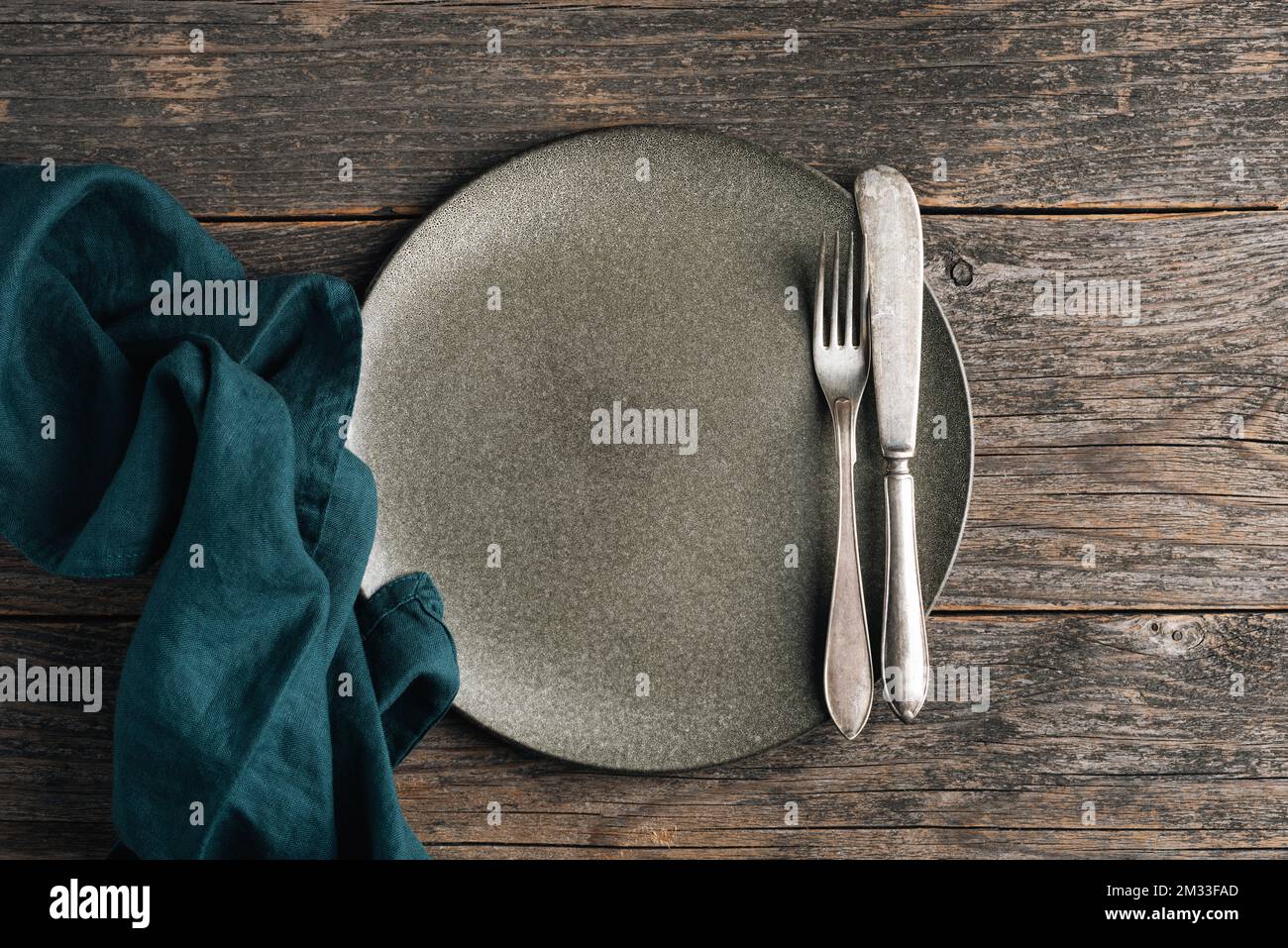 Argenteria vintage e piatto verde vuoto su fondo di tavolo in legno. Tavolo da pranzo impostazione. Vista dall'alto Foto Stock