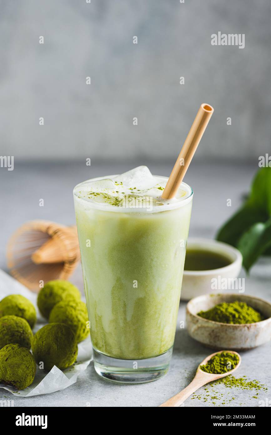 Ghiaccio freddo di latte di Matcha in vetro con paglia bevente di bambù. Bevanda vegana sana, alternativa al caffè. Copia spazio Foto Stock