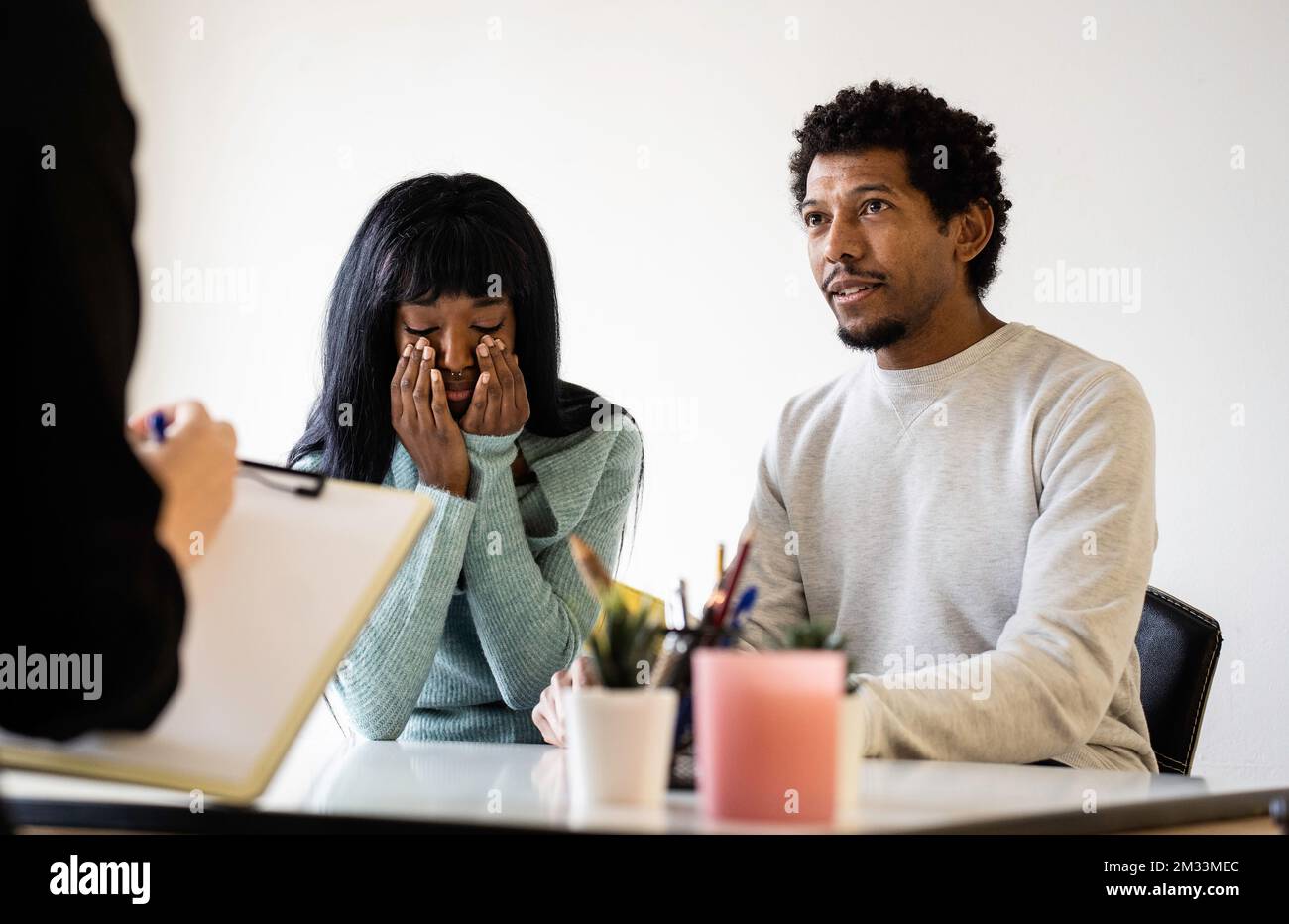 Coppia afro-americana seduta presso l'ufficio dello psicologo per una terapia di coppia - concetto di relazione di coppia in difficoltà e crisi - Focus sulla fa dell'uomo Foto Stock