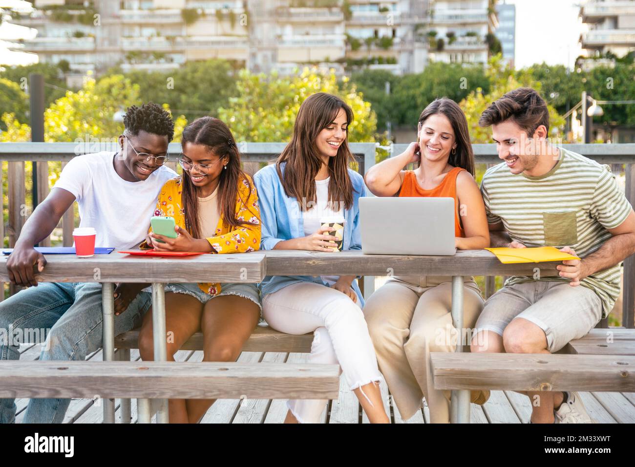 Allegro gruppo di studenti universitari che studiano per un esame nel campus - gruppo multiculturale di amici che lavorano insieme all'aperto. Foto Stock