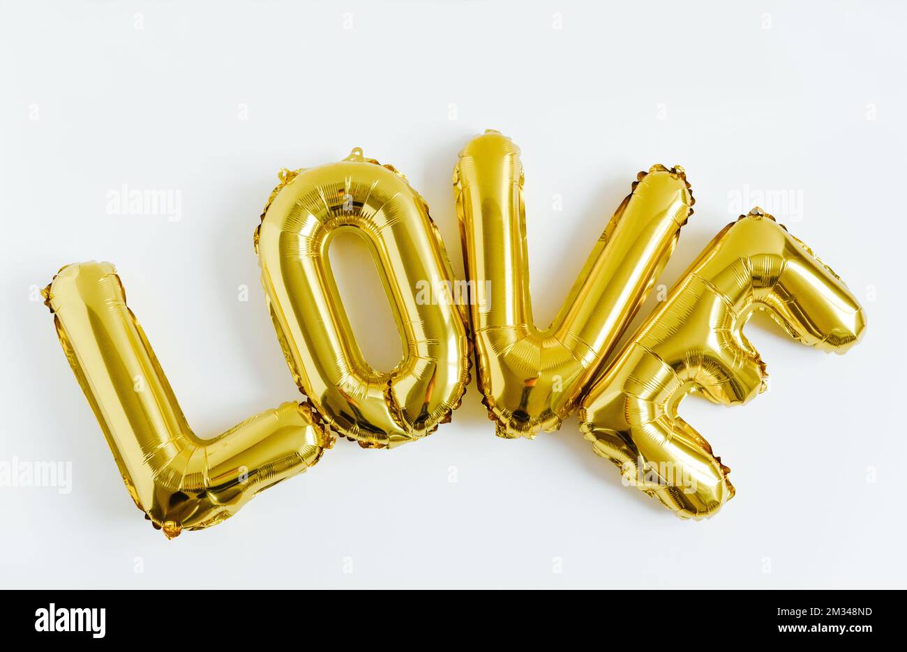 Iscrizione LOVE foil ballon dorato gonfiabile su sfondo bianco. Amore, romanticismo e San Valentino concetto Foto Stock