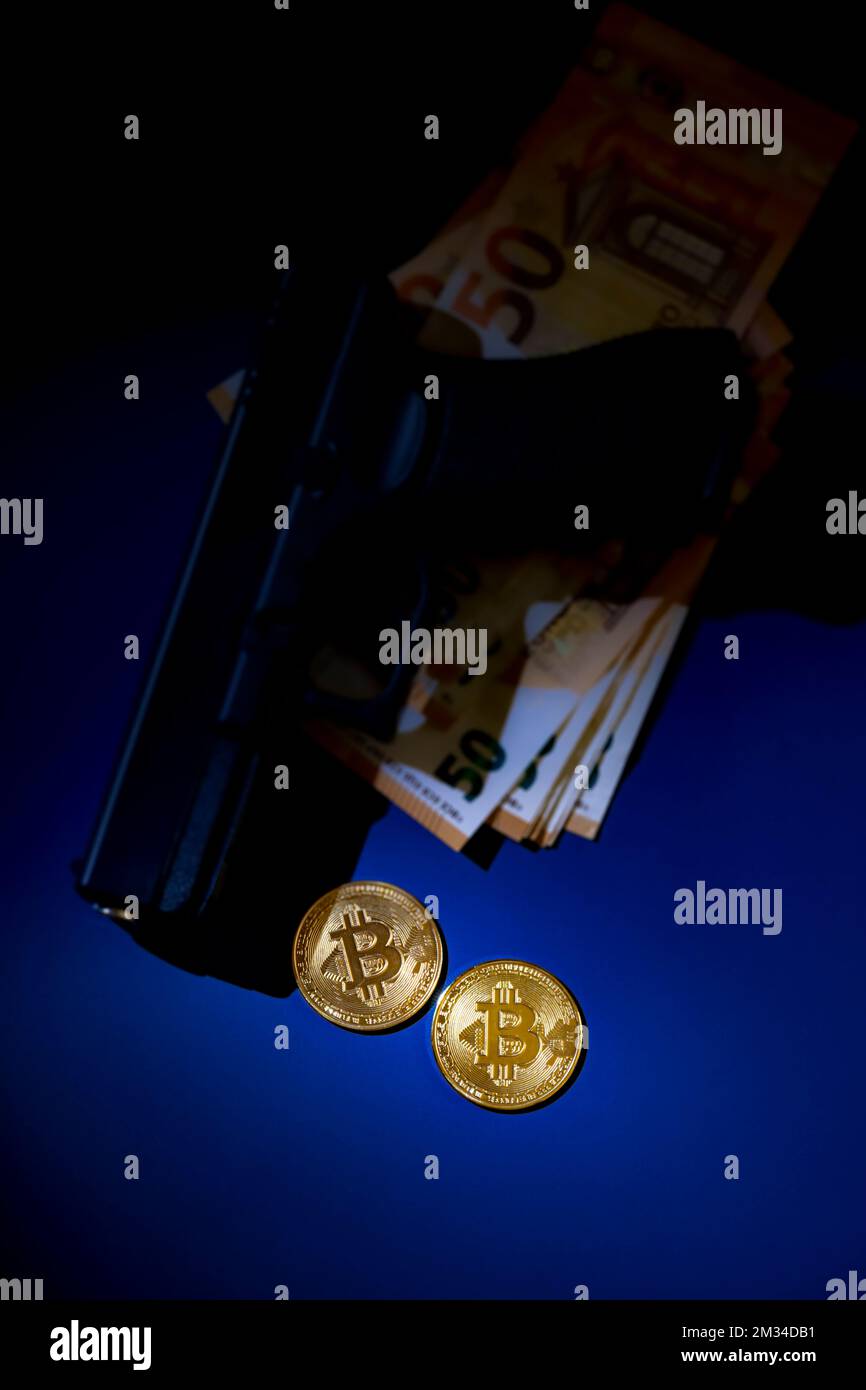 Monete bitcoin illuminate, con pistola ed euro, sfocate sullo sfondo, al buio. Fotografia e luci da studio Foto Stock