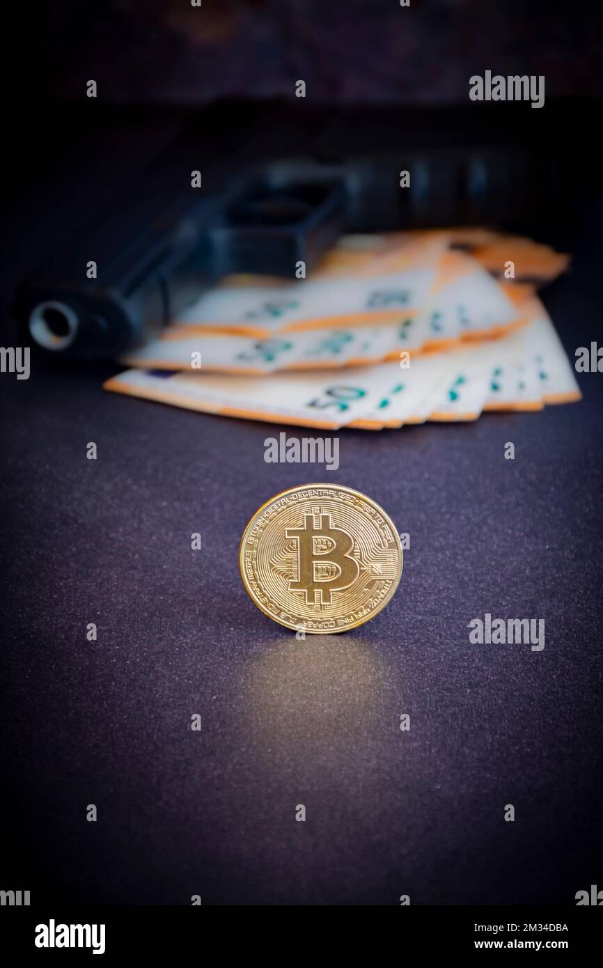 Bitcoin moneta in primo piano con una pistola e euro, defocused in background, nel buio. Fotografia e luci da studio Foto Stock