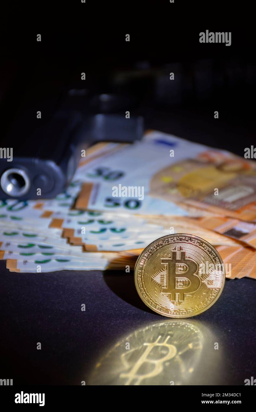 Bitcoin moneta in primo piano con una pistola e euro, defocused in background, nel buio. Fotografia e luci da studio Foto Stock