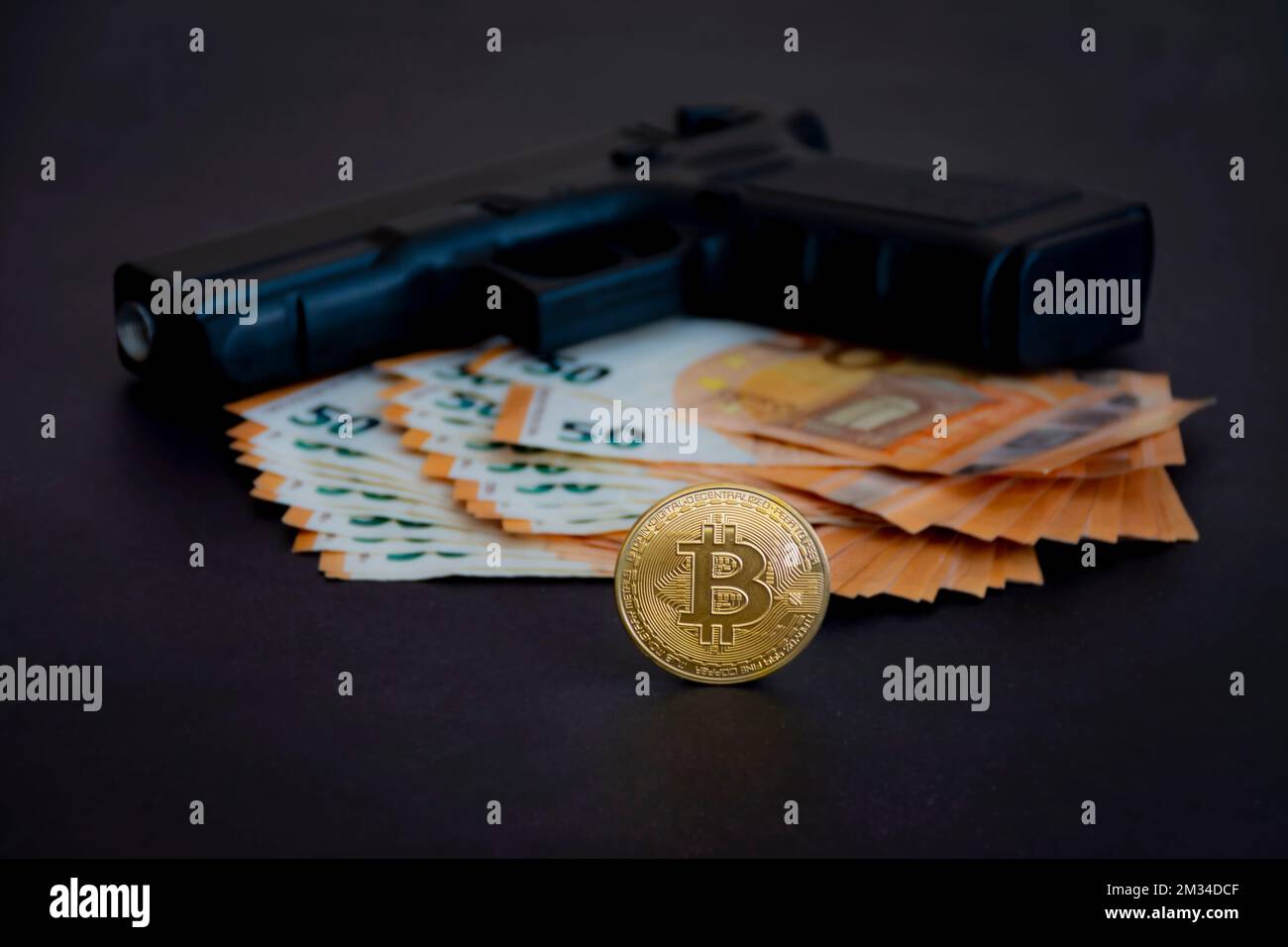 Bitcoin moneta in primo piano con una pistola e euro, defocused in background, nel buio. Fotografia e luci da studio Foto Stock
